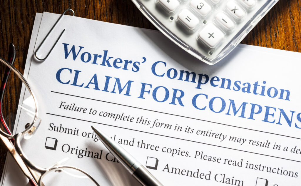 Workers' Compensation form with pen and glasses