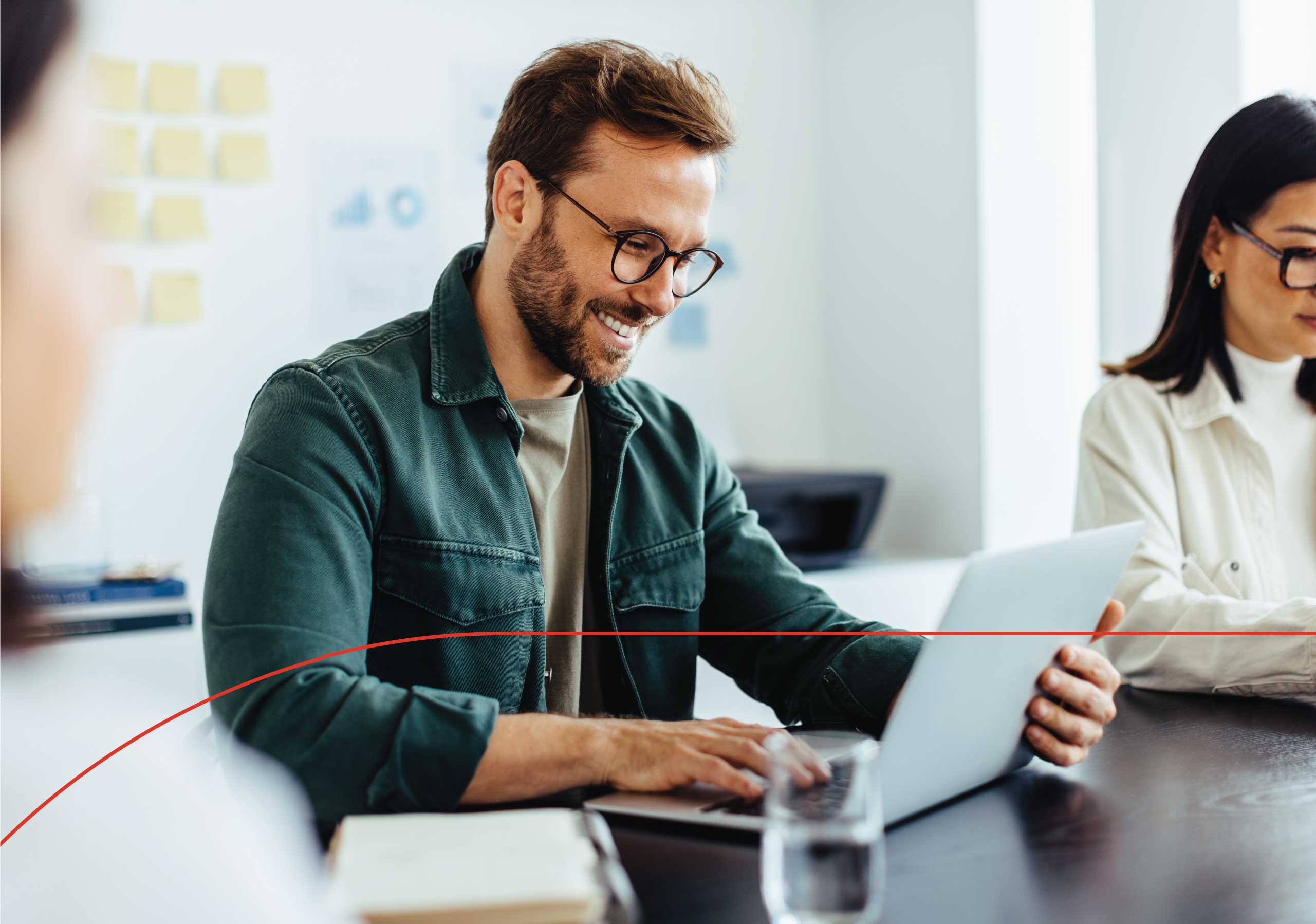 Male employee sitting in a conference room with other team members, reviewing employee benefits.