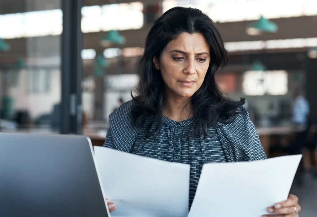 A woman reviews a professional liability insurance policy, making sure there is tail coverage.