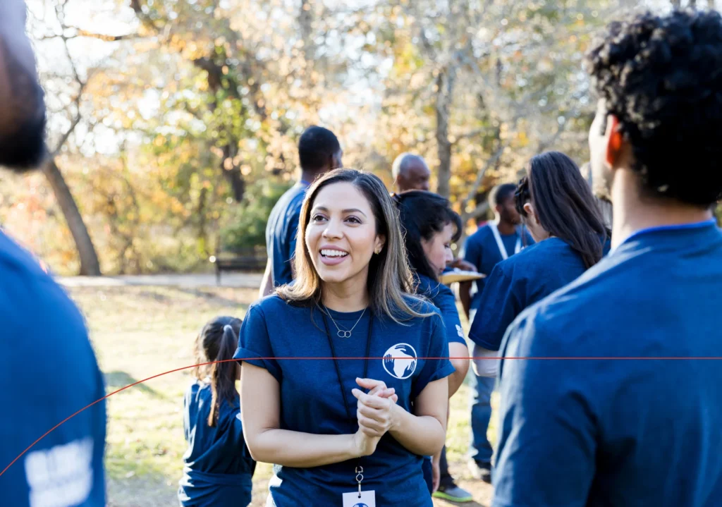 A woman speaks to a group of volunteers at an event.